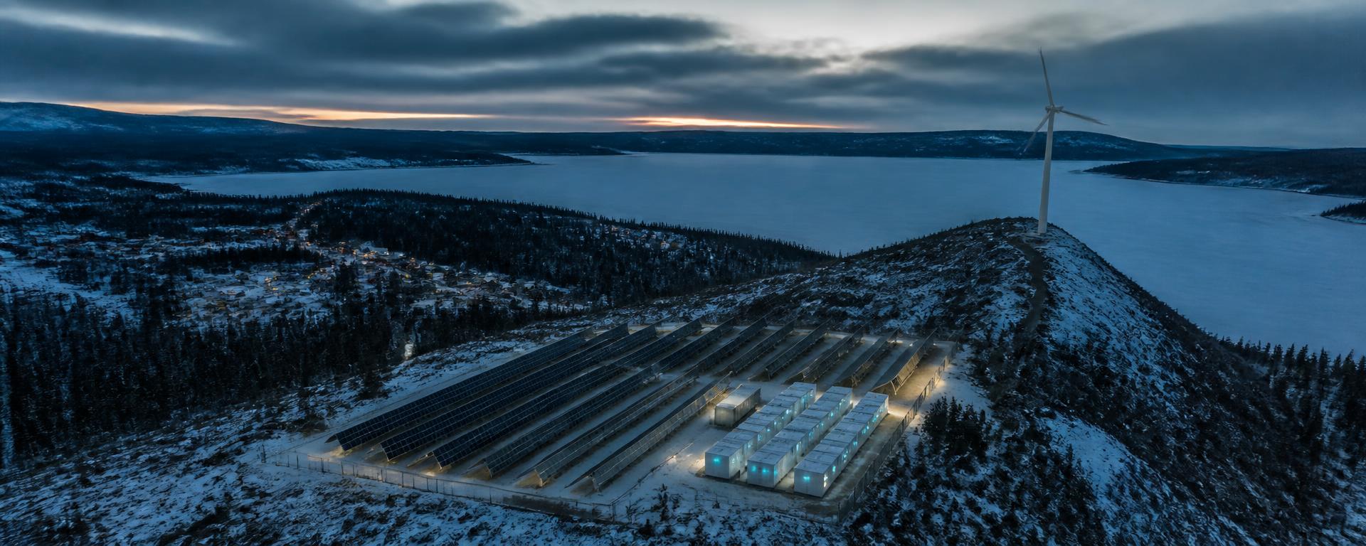 Solar, storage and wind serving a snow-covered northern community at dusk